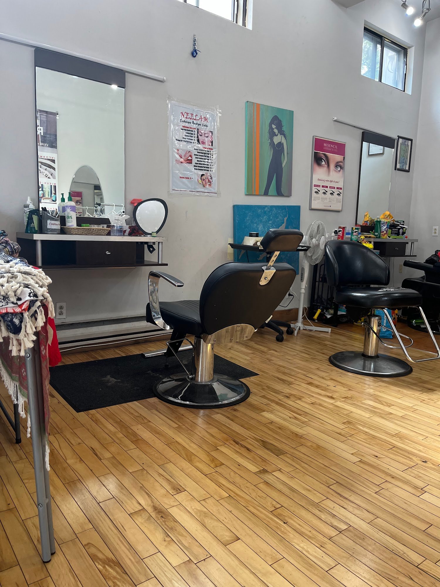 Intérieur du salon Neelam Esthetique sur le Plateau : fauteuils de coiffure, miroir et plancher de bois clair.
