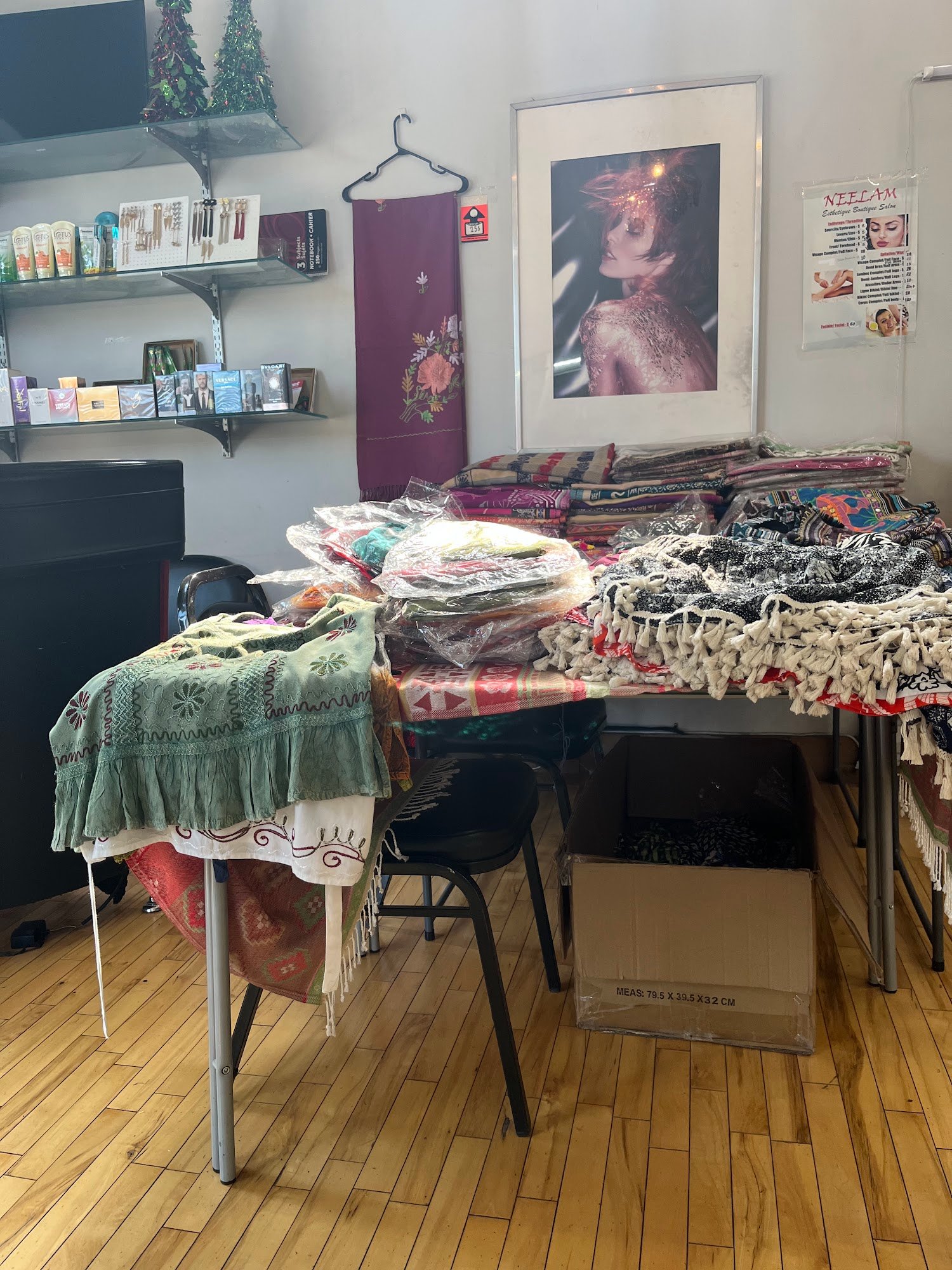 Coin boutique du salon Neelam : tables de foulards et textiles, tablettes de produits et affiche encadrée.